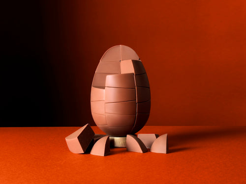 Unpackaged Belgian Milk Caramel Egg on a rich orange background